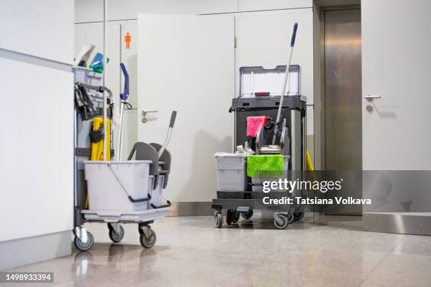 photo of cleaning cart with tools and buckets standing near restroom door at airport - impresa di pulizie foto e immagini stock