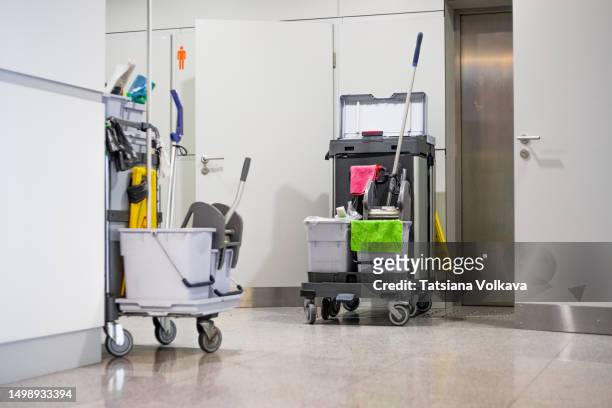 photo of cleaning cart with tools and buckets standing near restroom door at airport - serviços de limpeza imagens e fotografias de stock