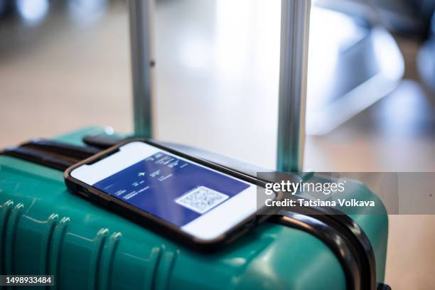close-up image of mobile phone screen displaying plane ticket lying on top of rolling suitcase - wheeled luggage stock pictures, royalty-free photos & images