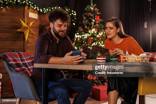 cheerful young man showing a meme to his girlfriend via smart phone - girlfriend meme stock pictures, royalty-free photos & images