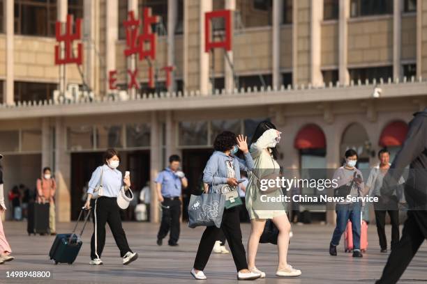 Citizens covering their foreheads with their hands walk by a railway station during a heat wave on June 16, 2023 in Beijing, China.
