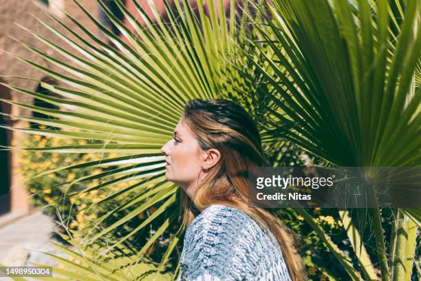 portrait of a blonde female with palm leaf outdoors - editorial - fotografias e filmes do acervo