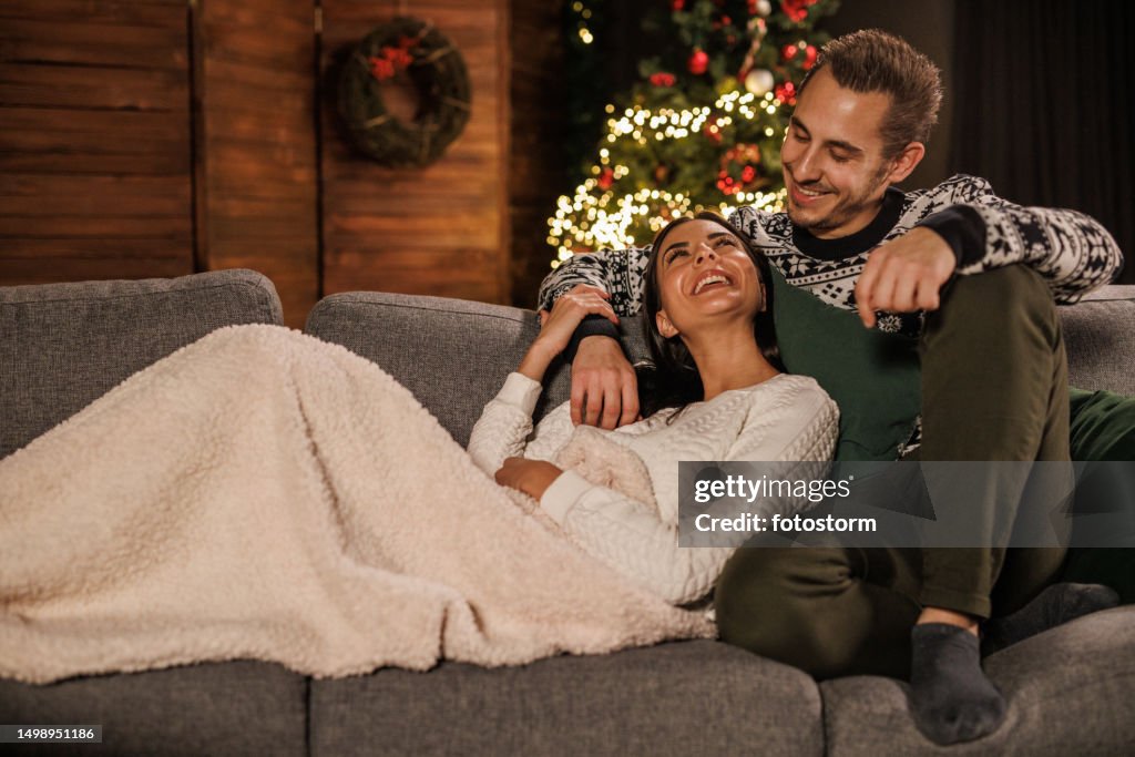 Romantic young couple cuddling and watching TV on a cozy winter's evening