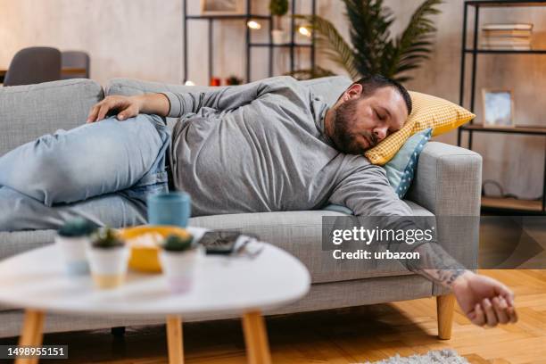 tired young man sleeping on the sofa - sleeper sofa bed stock pictures, royalty-free photos & images