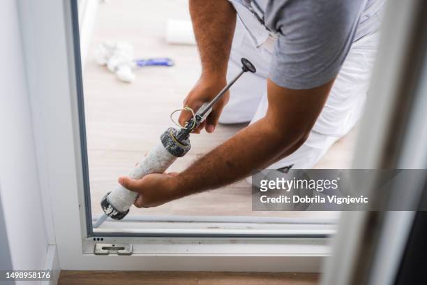 close-up of a handyman using silicone gun on balcony door - silikone stock pictures, royalty-free photos & images