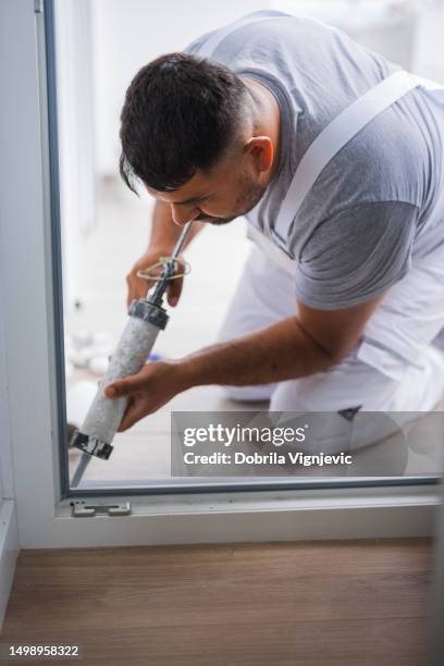 handyman using caulk gun when fixing balcony door - caulk gun stock pictures, royalty-free photos & images