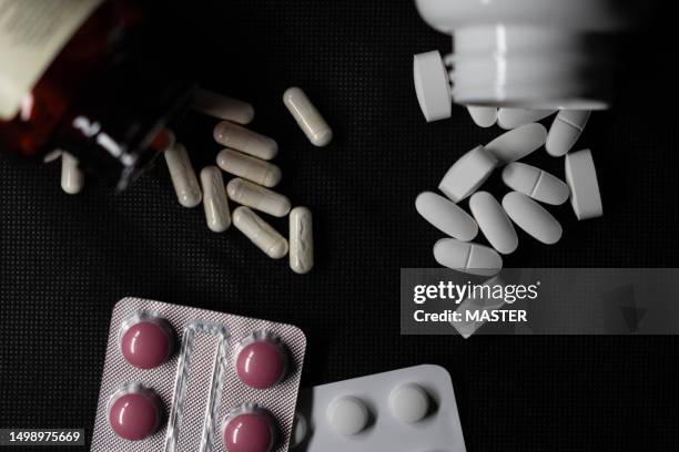 top view of pills and capsules spilling on black background with studio lightning - allergy medicine stock pictures, royalty-free photos & images