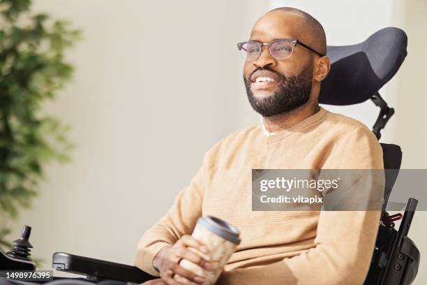 uomo nero disabile che utilizza lo smartphone a casa - simbolo internazionale di accesso foto e immagini stock