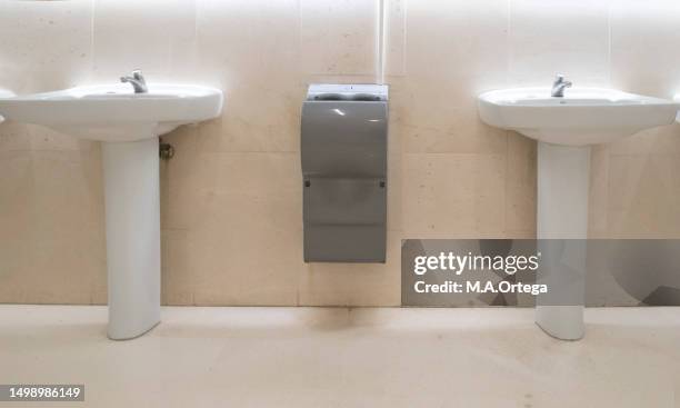 two sinks separated by a hand-drying device in a public restroom. - hand dryer stock pictures, royalty-free photos & images