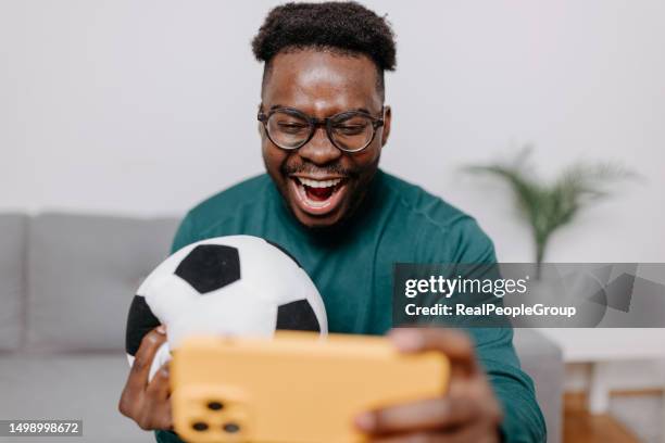 man embraces game, ball at his side for immersive experience - sports fans phone stock pictures, royalty-free photos & images