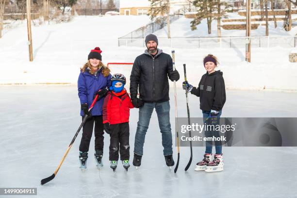 father & his three children ice skating in winter - hockey stick close up stock pictures, royalty-free photos & images