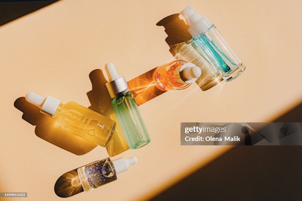 Assorted glass bottles with cosmetic liquids, serum or gel. Vibrant trendy background of cosmetic products