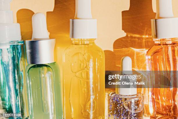 assorted glass bottles with cosmetic liquids, serum or gel. vibrant trendy background of cosmetic products - retinol stock pictures, royalty-free photos & images