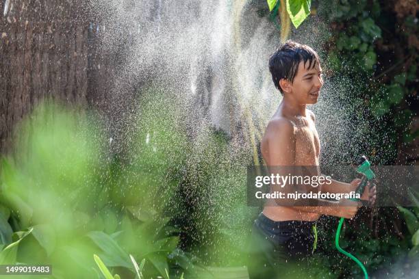 children in swimsuits playing with water from a hose - mjrodafotografia stock pictures, royalty-free photos & images