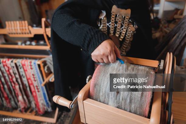 mapuche craft worker woman skillfully carding and processing sheep wool with a drum carder in her colorful workshop - indigenous american culture stock pictures, royalty-free photos & images