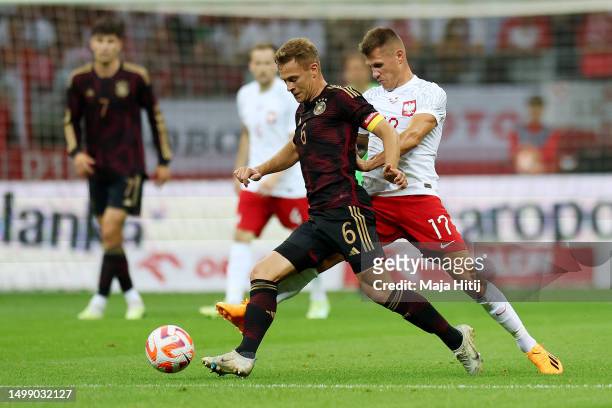 Joshua Kimmich of Germany is challenged by Damian Szymanski of Poland during the international friendly match between Poland and Germany at Stadion...