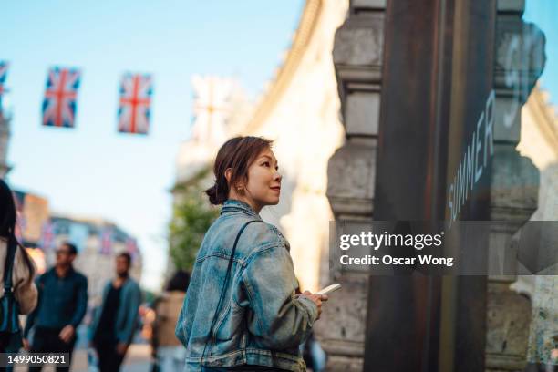 young asian woman doing window shopping on the high street - all european flags stock pictures, royalty-free photos & images