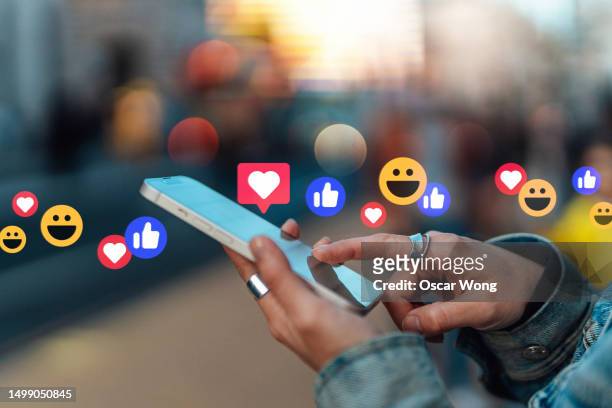 young asian woman checking social media with smartphone on city street - social media stock pictures, royalty-free photos & images