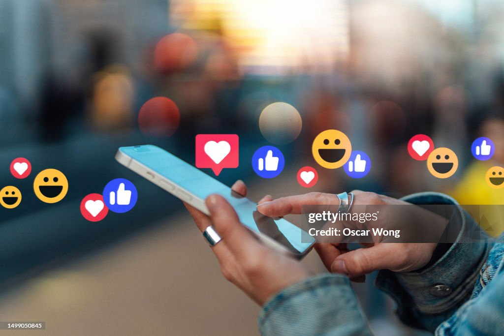 Young Asian woman checking social media with smartphone on city street