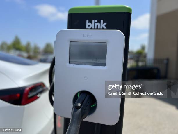 White car charging at a Blink station with clear sky in the background, CarMax, Fairfield, California, May 25, 2023.