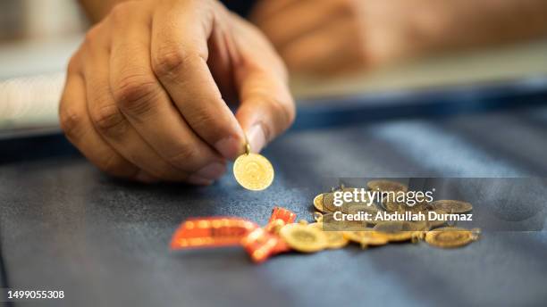 man hand holding 1/4 turkish gold - juwelier stockfoto's en -beelden