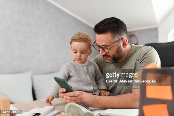 father introducing baby boy to the ins and outs of smartphones - call outs stock pictures, royalty-free photos & images