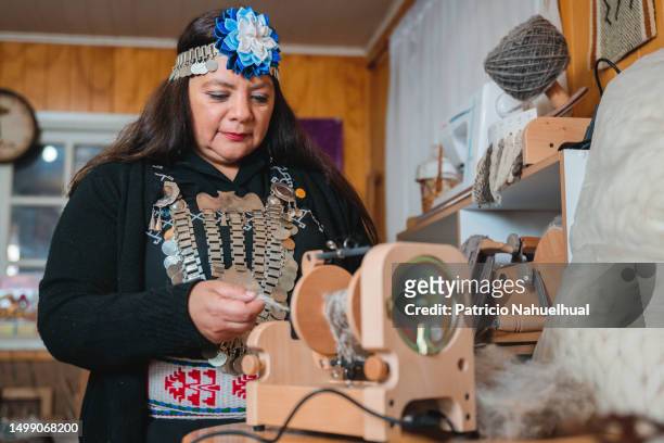 smiling mapuche craft worker woman using an electric yarn spinner machine, to spin sheep wool in her home textile workshop - indigenous american culture stock pictures, royalty-free photos & images