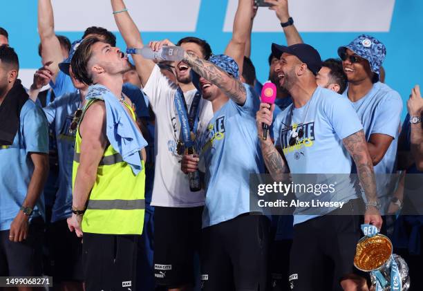 Kalvin Phillips of Manchester City pours Grey Goose into the mouth of Jack Grealish as they celebrate on stage in St Peter's Square during the...