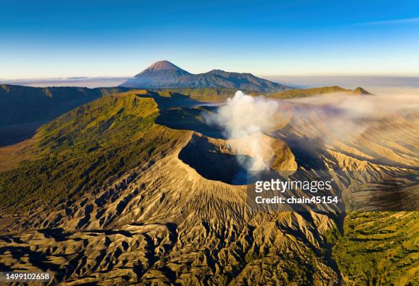 breath of bromo. aerial view from drone of bromo volcano with smoke in the morning sunrise. east java, indonesia. - vulkan rinjani stock-fotos und bilder
