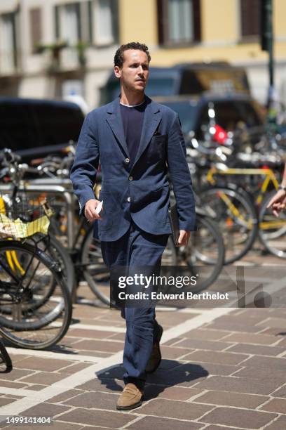 Guest wears a navy blue t-shirt, a navy blue blazer jacket, matching navy blue suit pants, beige suede loafers, outside Valentino, during the Milan...