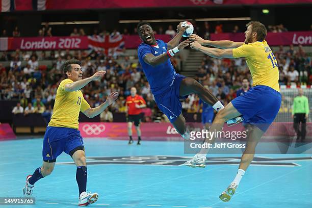 Luc Abalo of France jumps to shoot while Dalibor Doder and Jonas Larholm of Sweden can just watch on during the Men's Handball preliminaries group A...