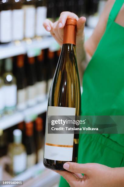 close-up view of dark bottle of wine in hands of unrecognizable lady in store - choosing wine stock pictures, royalty-free photos & images