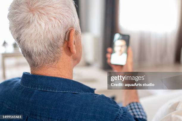 senior man with hearing aid having video conference - inner ear stock pictures, royalty-free photos & images