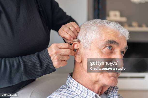 caregiver che aiuta l'uomo anziano con l'apparecchio acustico - gusto foto e immagini stock