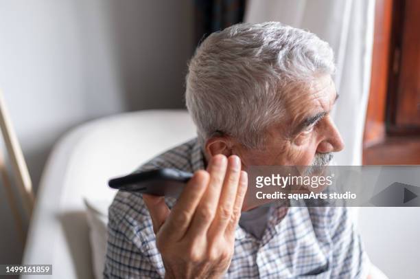 senior man with hearing aid using smartphone - first gray hair stock pictures, royalty-free photos & images