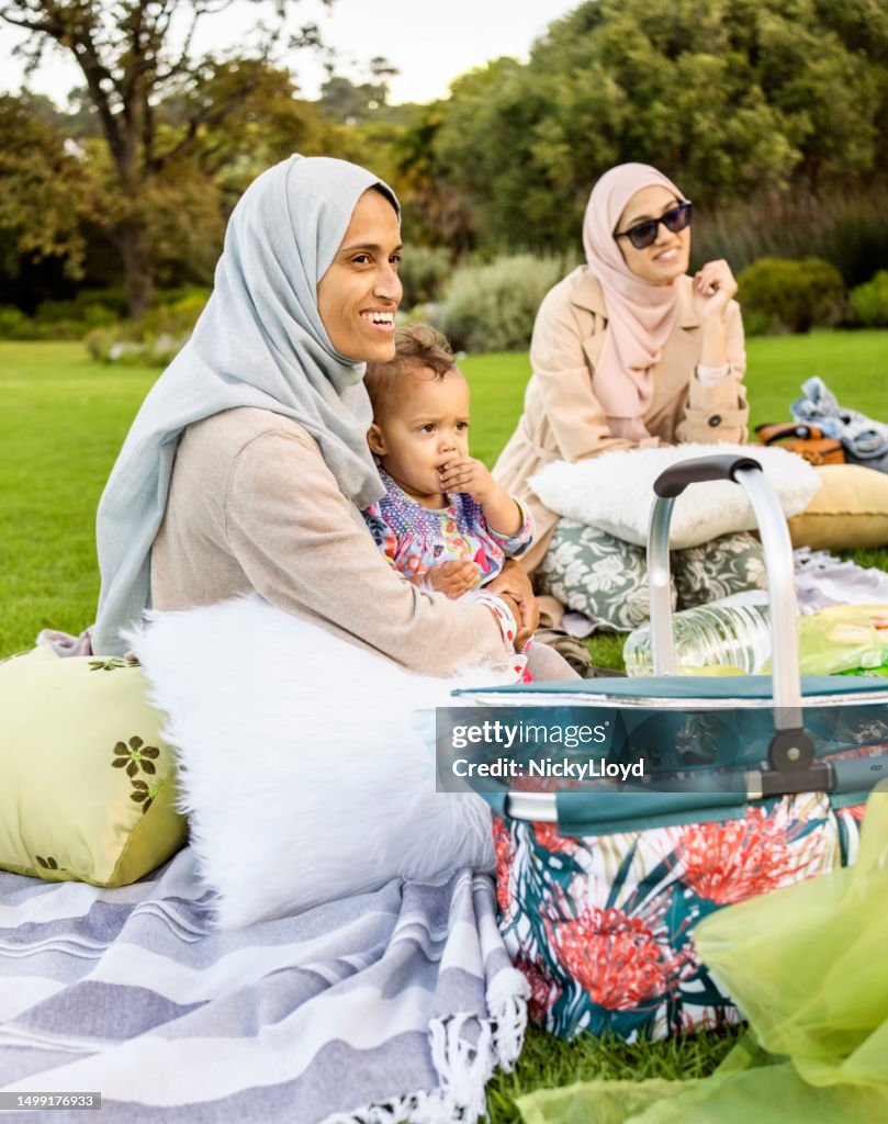 Islamic woman siting with her son and friend on picnic at park