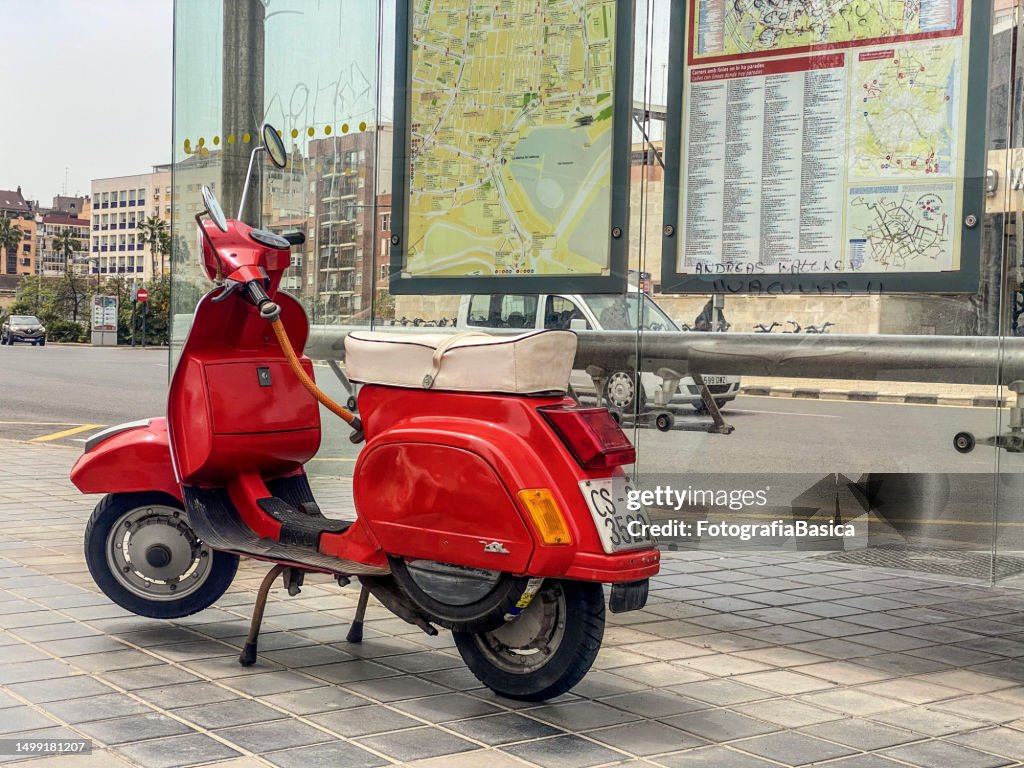Roter Motorroller neben Bushaltestelle geparkt