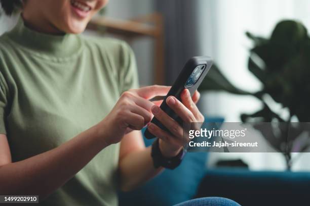 close-up shot of female hands using smart phone sitting on sofa in living room at home. - finger dialing touch tone telephone stock pictures, royalty-free photos & images