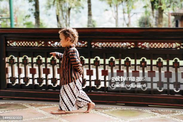 young kid using surjan (yogyakarta tradition dress) playing at the joglo house - batik dress stock pictures, royalty-free photos & images