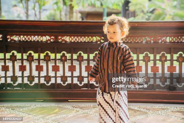 young kid using surjan (yogyakarta tradition dress) playing at the joglo house - batik dress stock pictures, royalty-free photos & images