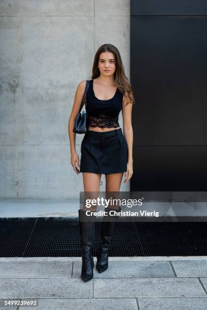 Guest wears black laced top, mini skirt, boots, bag outside Neil Barrett during the Milan Fashion Week - Menswear Spring/Summer 2024 on June 17, 2023...