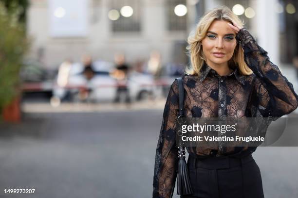 Veronica Ferraro is seen wearing a black see-thought lace long sleeves shirt, black hight waist trousers and a black leather bag with silver details...