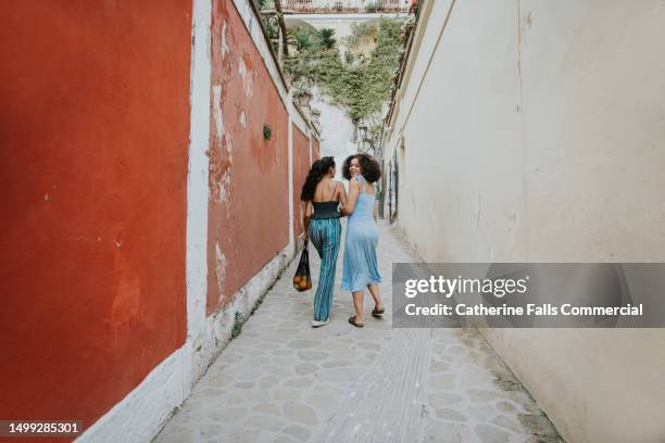 two female friends on vacation link arms, and explore positano, italy - wide shot stock pictures, royalty-free photos & images