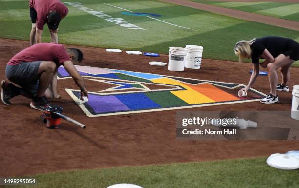 Arizona Diamondbacks grounds crew and staff members use colored sand to decorate the team logo in conjunction with Pride Night at Chase Field during...