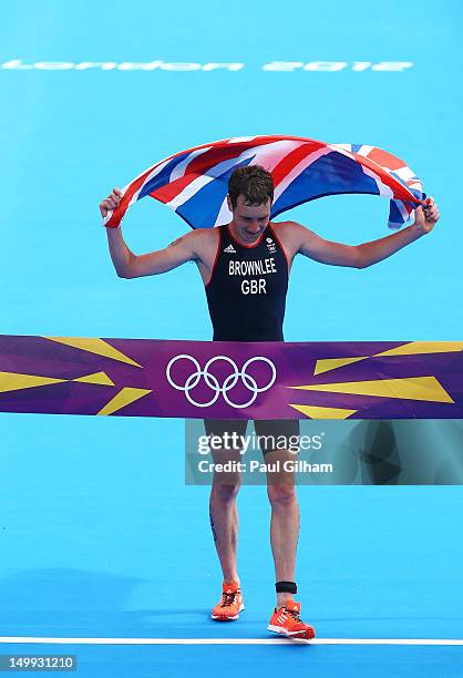 Alistair Brownlee of Great Britain holds a union jack aloft as he celebrates crossing the finish line and winning gold during the Men's Triathlon on...