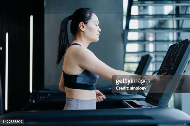 asian girl is setting the speed on the treadmill - real body fotografías e imágenes de stock