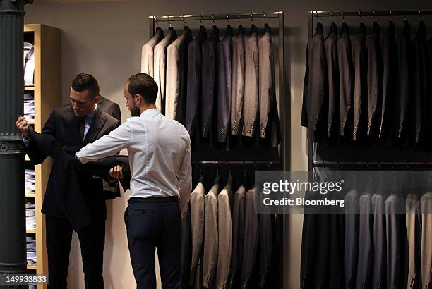 Employees inspect a suit for sale at the Gieves & Hawkes store, owned by Trinity Ltd., on Saville Row in London, U.K., on Tuesday, Aug 7, 2012. U.K....