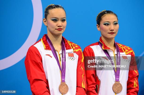 China's Liu Ou and China's Huang Xuechen react on the podium after winning bronze in the duets free routine final during the synchronised swimming...
