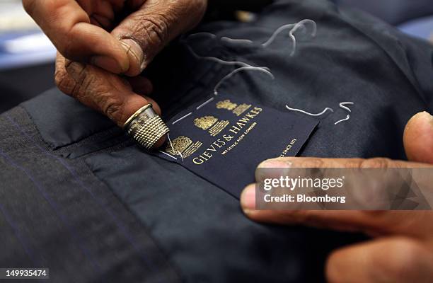 An employee sews a label into a suit jacket in the workshop at the Gieves & Hawkes store, owned by Trinity Ltd on Savile Row in London, U.K., on...