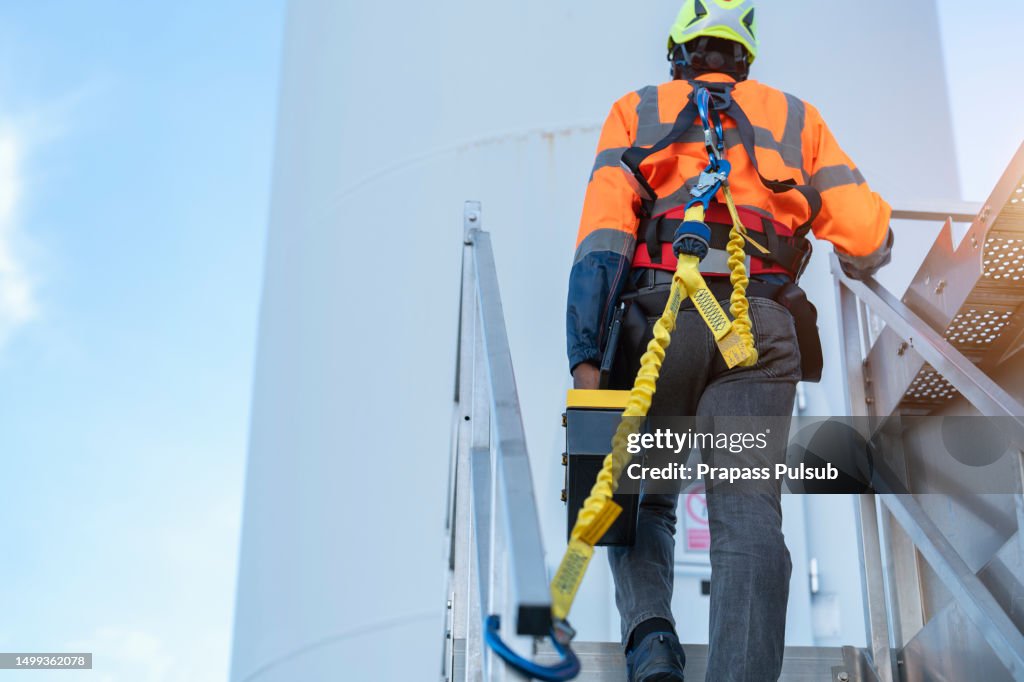 Worker wearing safety harness and safety line working at high place
